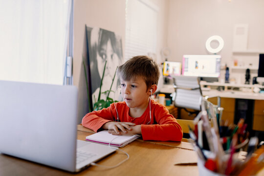 Young boy concentred looking at a computer screen during remote classes at home