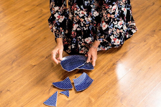 Close-up of woman picking up a broken plate 