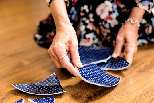 Close-up of woman picking up a broken plate 