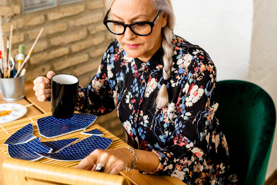 Portrait of hoary woman repairing a broken plate with a millenial japanese technique 