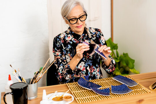 Portrait of hoary woman repairing a broken plate with a millenial japanese technique 