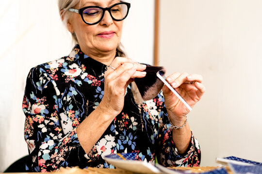 Portrait of hoary woman repairing a broken plate with a millenial japanese technique 