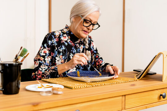 Portrait of hoary woman repairing a broken plate with a millenial japanese technique 