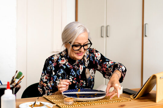 Portrait of hoary woman repairing a broken plate with a millenial japanese technique 