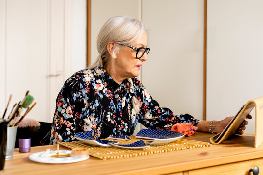 Portrait of hoary woman repairing a broken plate with a millenial japanese technique 