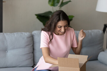Excited Arabian woman received parcel, internet store order, showing yes gesture, celebrating...