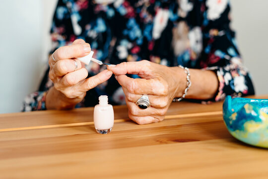 Senior woman painting the nails at home 