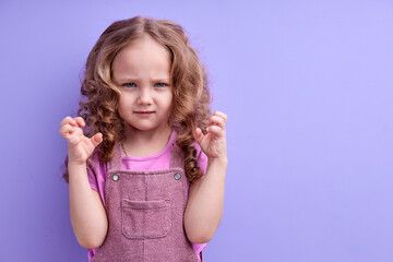 Portrait of serious kid girl looking at camera, tired upset school child with thoughtful face, irritated by something, posing isolated over purple studio background. copy space