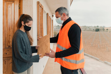 Delivery man with mask delivers package to customer.