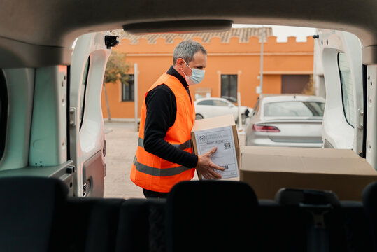 Shipment: Man with mask Getting Boxes Out Of Delivery Van