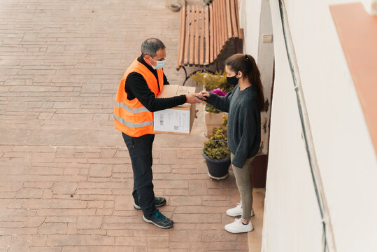 Delivery man with mask delivers package to customer.