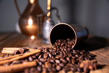 A cup of coffee on a wooden table from old boards. Scattered coffee beans and cinnamon.