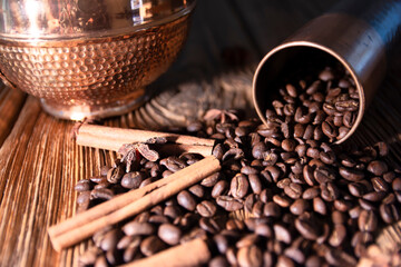 A cup of coffee on a wooden table from old boards. Scattered coffee beans and cinnamon.