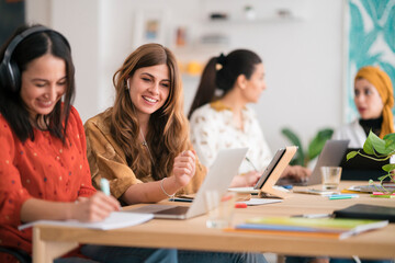 Smiling young multiracial female friends working together in office