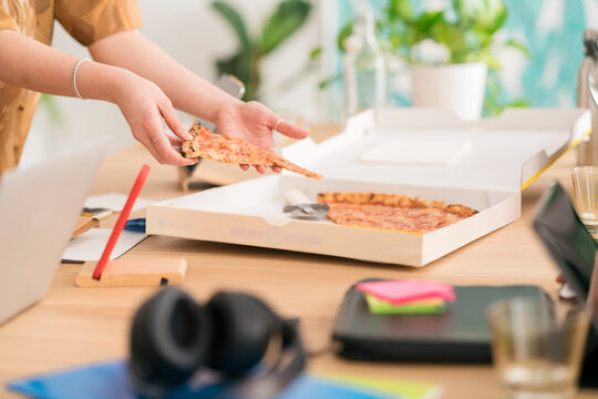 Female taking piece of pizza for lunch