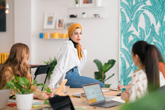Serious young Arab female working with colleagues in creative office