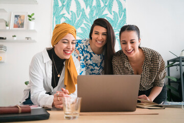 Female colleagues talking on video chat on laptop in office