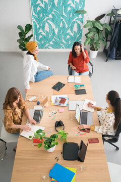 Diverse female colleagues discussing business strategy at table in workspace