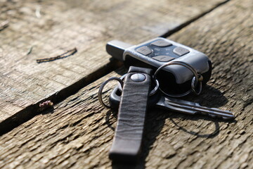 old car keys and car alarm keychain on a wooden table close up