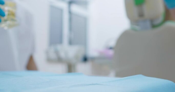 Two jaw models are standing on the table and one is with straight ceramic teeth, other is with crooked teeth and a bracket system. They are taken from the table by two medical workers.