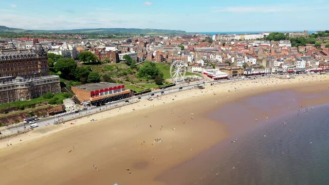 Aerial drone footage of the beach front in the town of Scarborough in North Yorkshire, England UK showing people relaxing and having fun on the beach on a sunny summers day
