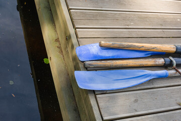 Classic wooden boat oars. Plastic boat paddles lie on a wooden pier, boat rental in the park