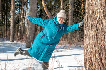 Grandmother walks in nature in winter. Cheerful elderly woman.