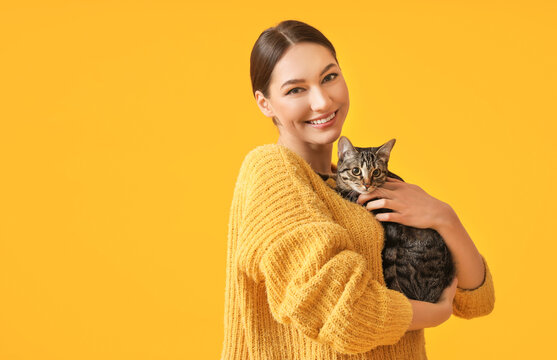 Beautiful young woman with cute cat on color background