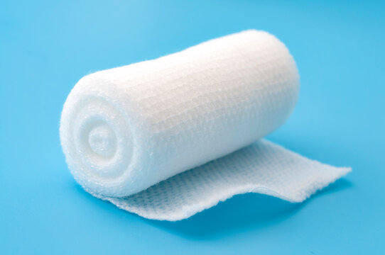 First aid, injury protecting wrapping and wound dressing concept clean cotton gauze bandage isolated on blue background