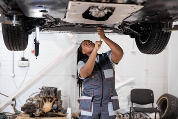 African female auto mechanic fixing car, mechanic repairing car on lift in garage. attractive...