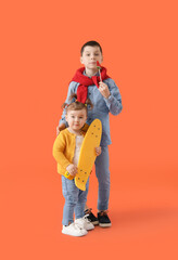 Cute little children with skateboard on color background