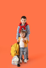 Cute little children with backpacks on color background