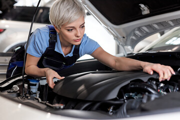 Cute Female auto mechanic examine car engine breakdown problem in front of automotive vehicle car...