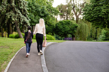 Mother taking daughter to school. Back view.