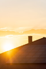 Real photo of photovoltaic panels on the roof of the house against the setting sun. Background with copy space in warm, sunny tones, perfect for solar energy materials - 439411286