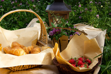 morning picnic outside.there is a strawberry ,croissantin the basket and flowers