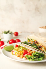 Plate with tasty vegetarian tacos on light background