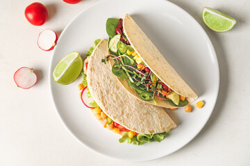 Plate with tasty vegetarian tacos on light background