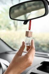 Female hand with air freshener hanging in car, closeup