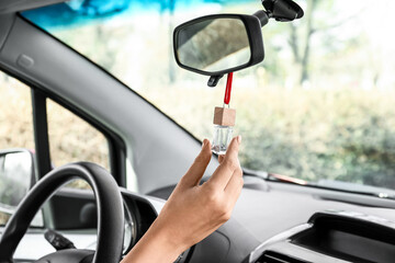 Female hand with air freshener hanging in car