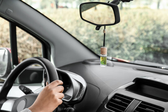 Young Woman Holding Hands On Steering Wheel And Air Freshener Hanging In Car