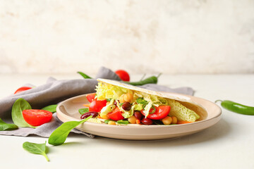 Plate with tasty vegetarian taco on light background