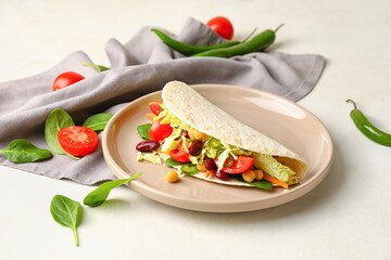 Plate with tasty vegetarian taco on light background