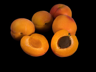 A bunch of ripe Apricot fruits, whole and slices, on a black background in isolation