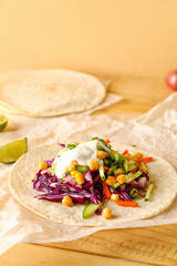 Parchment with tasty vegetarian taco on wooden background
