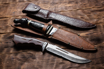 Hunting knives on the old wooden table background.