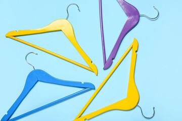 Stylish clothes hangers on color background