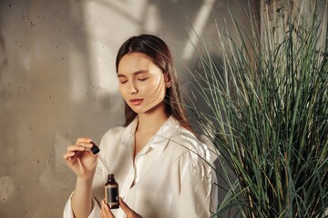 Woman hands holding massage or cosmetics oil bottle for applying drops to skin of face