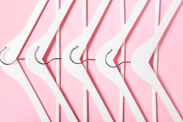 Stylish clothes hangers on color background