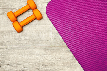 Fitness pink sports mat and dumbbell for the home exercises. Yoga concept and backgrounds